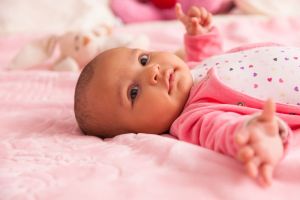 Cute newborn baby dressed in pink laying in crib