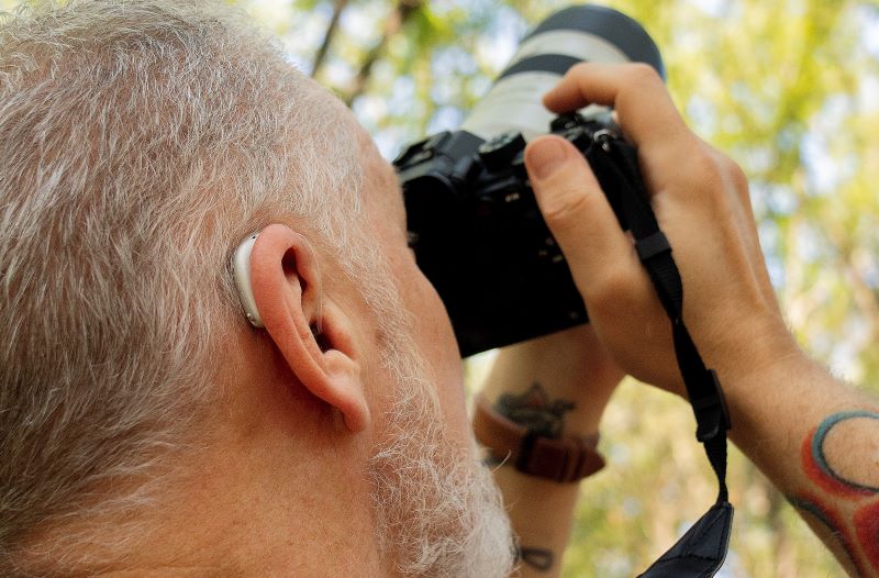 A photographer looks for birds while wearing a hearing aid. 