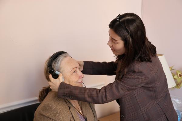 Dr. placing testing headphones on patient