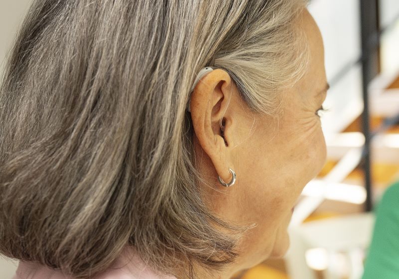 A woman wears a RIC hearing aid