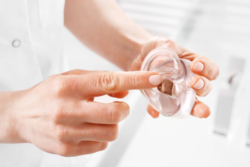 a woman points to an in-the-canal hearing aid.