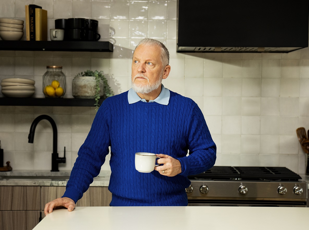 A man looks at hearing aids at a hearing care appointment with his wife. 